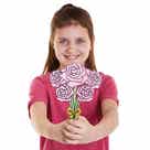 Bloemen Boeketten Van Hout: lachend meisje houdt een houten bos roze bloemen met groene stelen en gele strik tegen witte achtergrond